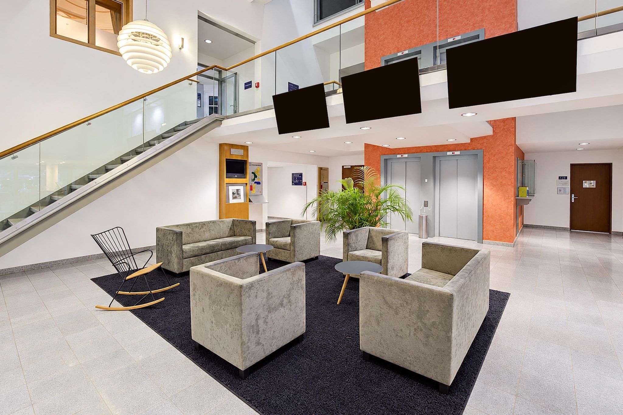 Eine moderne Lobby mit Treppe, Sitzgelegenheit und einer großen Pflanze.