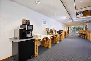 A modern coffee station with a coffee machine, cups, and a wooden table.