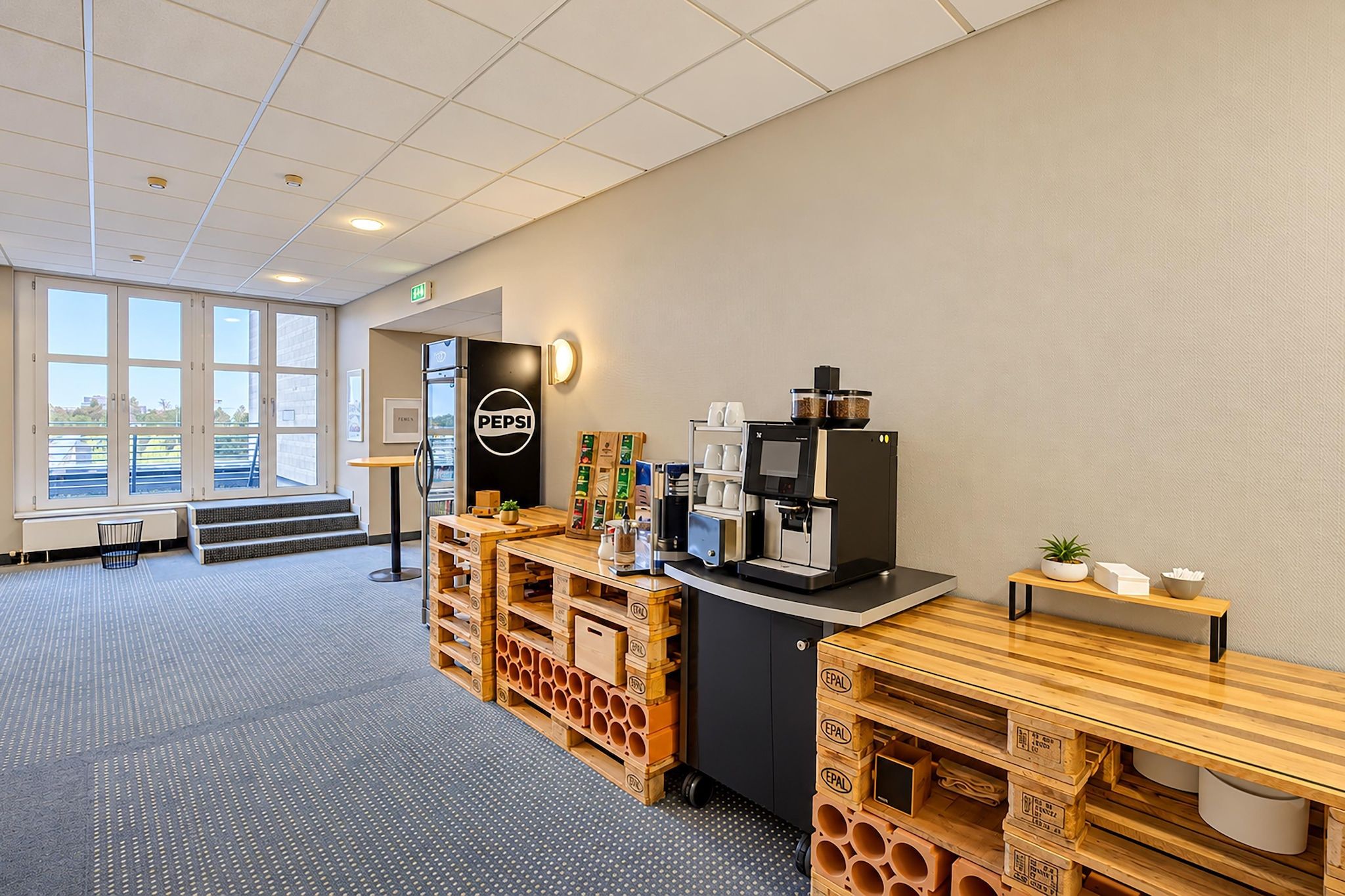 A modern coffee station with a Pepsi refrigerator, coffee machine, and storage shelves.