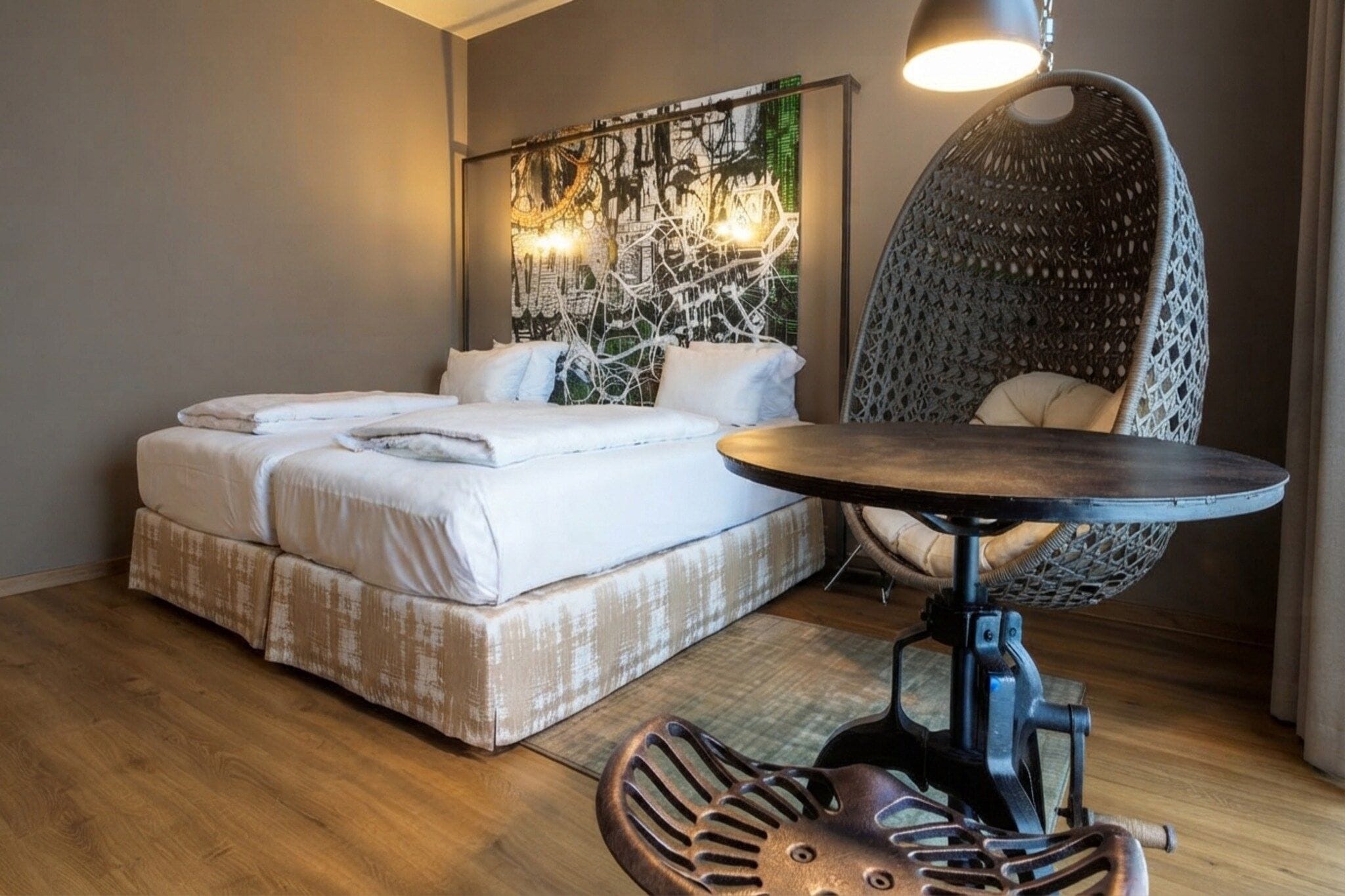 A hotel room with a bed, a round table, a chair, and a wall art piece.