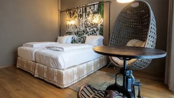 A hotel room with a bed, a round table, a chair, and a wall art piece.