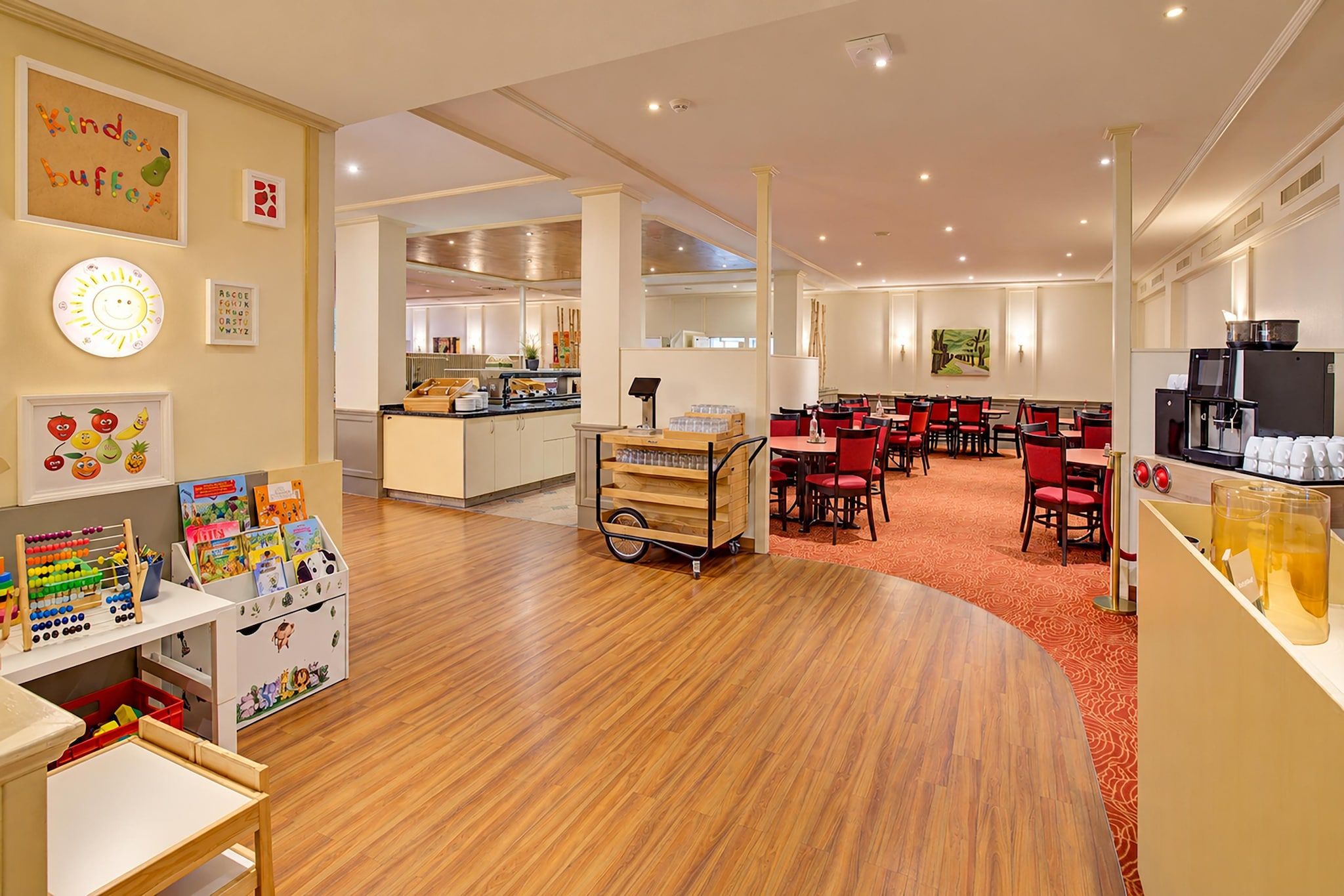 Een kinderspeelruimte met educatief speelgoed en een kitchenette met een buffetopstelling.