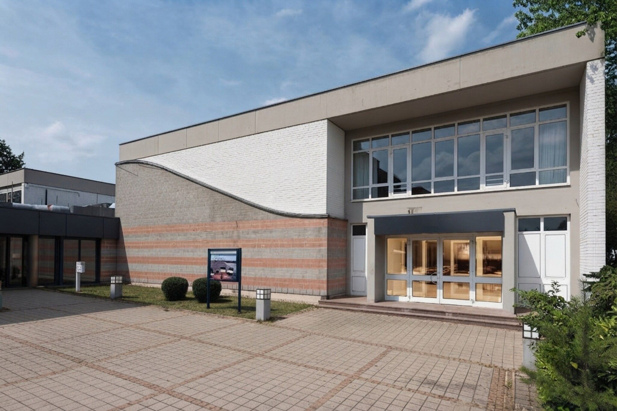 A modern building with a flat roof, large windows, and a brick facade.