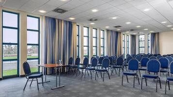 A conference room with rows of chairs, a table, and large windows.