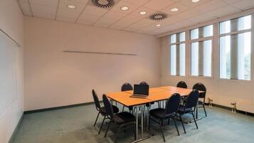 A conference room with a long table, six chairs, and a laptop on the table.