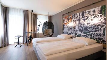 Ein modernes Hotelzimmer mit einem großen Bett, einem Hängesessel und einer Wand mit Graffiti-Kunst.