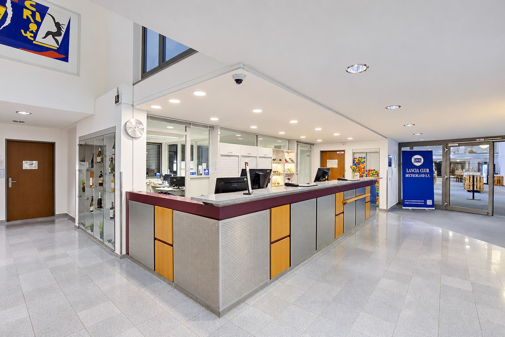 En moderne reception med et digitalt skærm, et ur og et overvågningskamera.