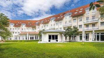 A multi-story building with a red-tiled roof, a central courtyard with a bench, and a grassy area.
