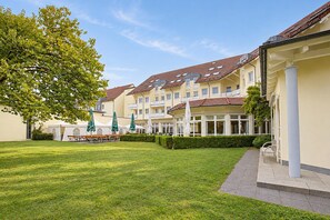 A courtyard with a lawn, outdoor seating, and a building with multiple windows and balconies.