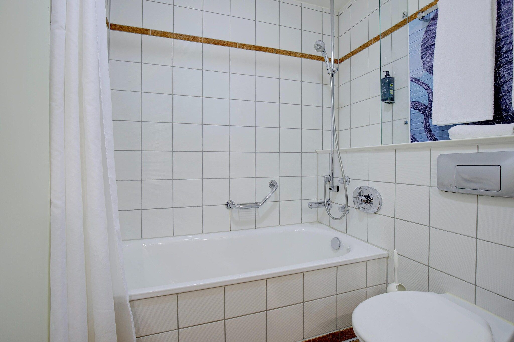A bathroom with a white bathtub, a toilet, and a shower area.
