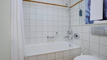 A bathroom with a white bathtub, a toilet, and a shower area.