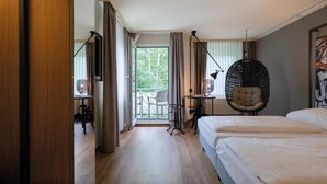 Hotellihuone, jossa on parveke, riipputuoli ja työpöytä lampun kanssa.