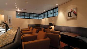 A hotel lounge with seating, a bar area, and a view through a large window.