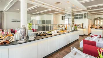 Ein Buffetbereich mit vielfältigen Speisen, ein Sitzbereich mit Tischen und Stühlen sowie ein modernes Decken-Design.