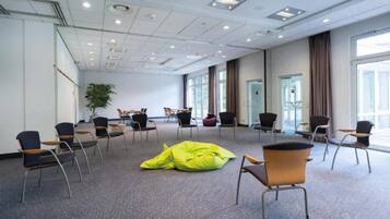 A conference room with multiple chairs, a large window, and a plant.