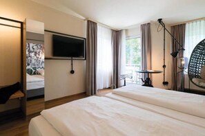 A hotel room with two beds, a flat-screen TV, a small table, and a chair.