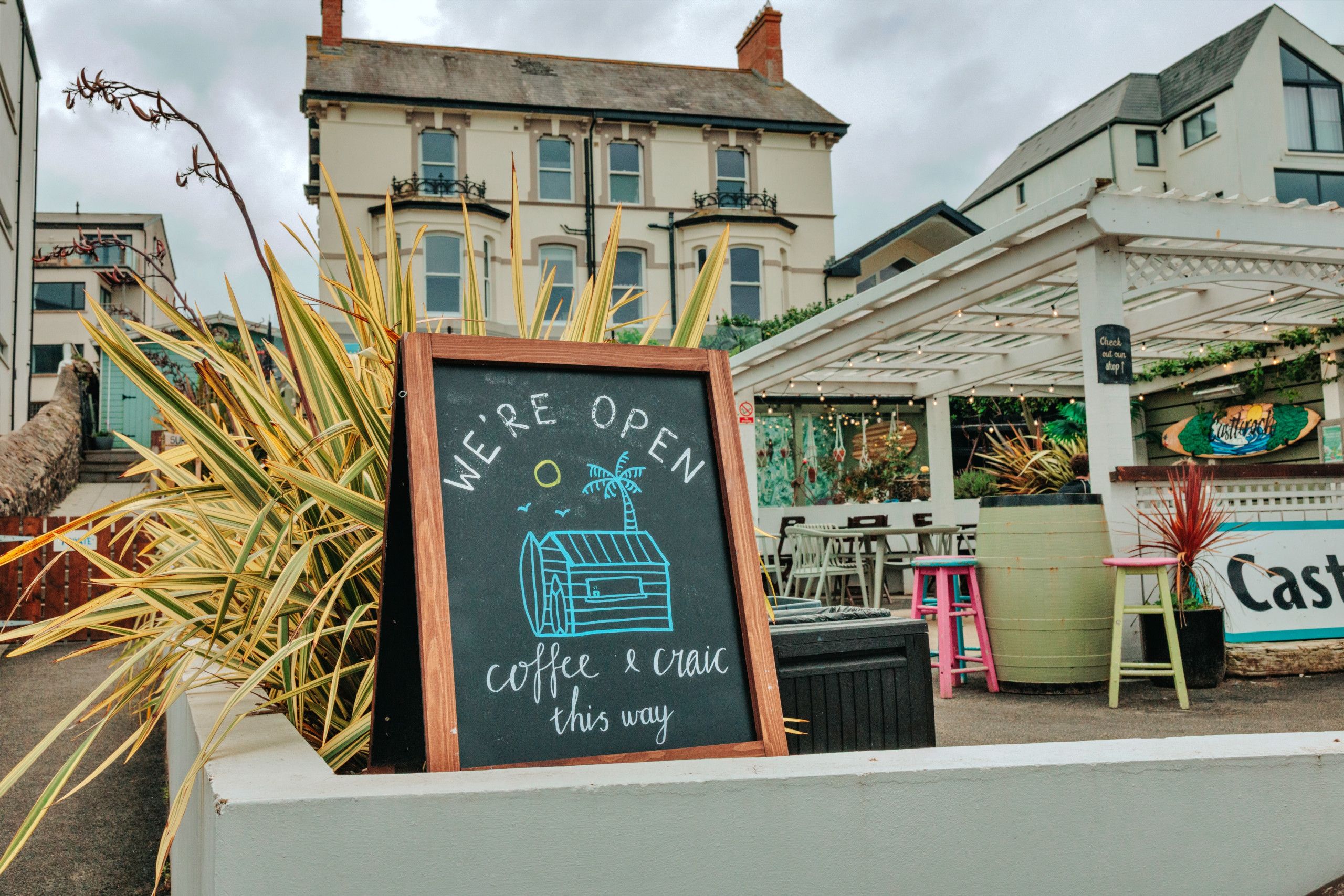 A chalkboard sign with 'WE'RE OPEN' and 'Coffee & Cake this way' indicating a cafe's location. - Pebble House (Castlerock)