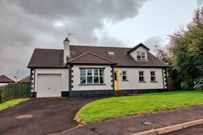 A two-story house with a garage, a front door, and a small garden. - Pebble House (Castlerock)