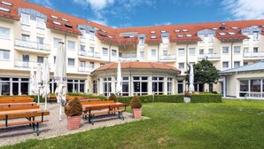 Un hotel de varios pisos, con mobiliario exterior y un jardín bien cuidado.