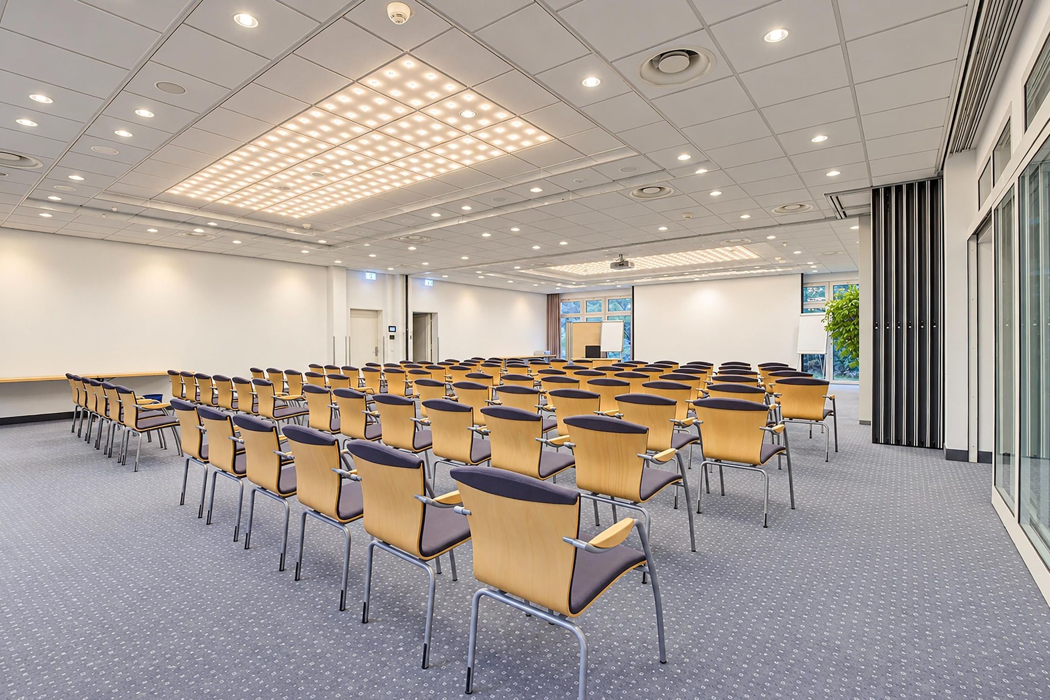 A conference room with rows of chairs, a projector screen, and a large window.