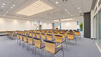 A conference room with rows of chairs, a projector screen, and a large window.