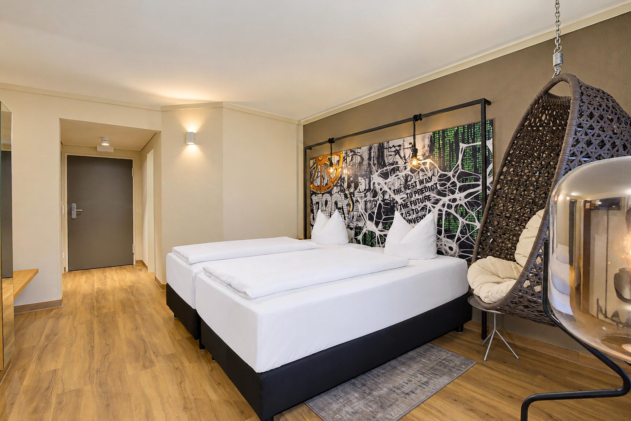 Ein Hotelzimmer mit Doppelbett, Hängesessel und Wand mit Graffiti-Kunstwerk.
