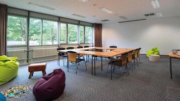 A conference room with a large table, chairs, bean bags, and a view of trees through the windows.