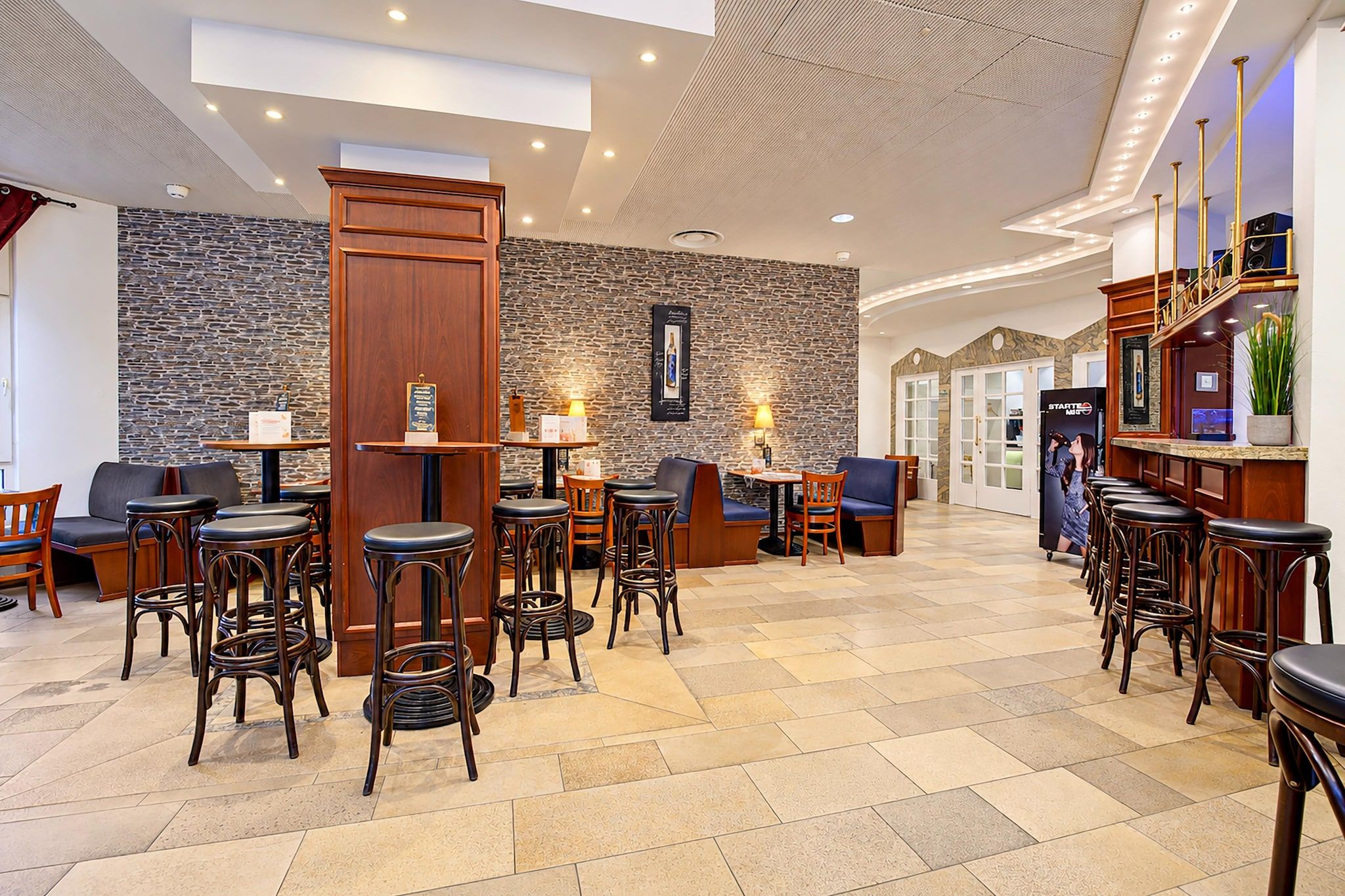Un hall de hotel con zona de bar, asientos y una pared de piedra.