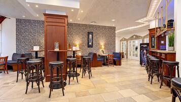 Un hall de hotel con zona de bar, asientos y una pared de piedra.