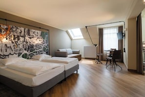 Moderni hotellihuone, jossa on suuri sänky, työpöytä ja taulu seinällä.