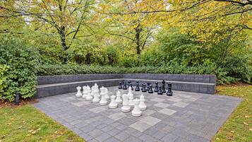 A chessboard set outdoors surrounded by a brick wall and greenery.