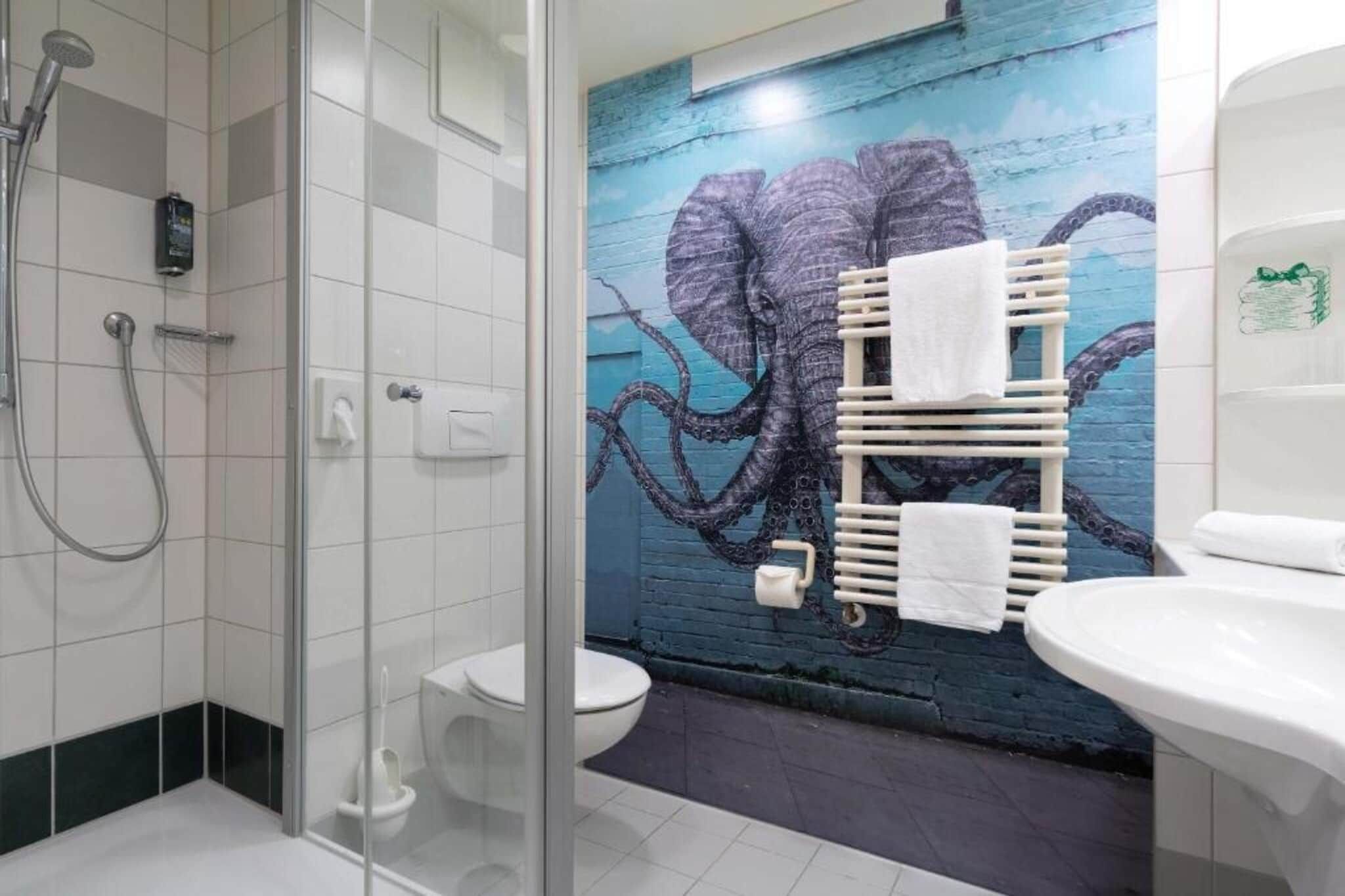 Une salle de bain avec une douche à parois de verre, des toilettes et un lavabo.
