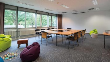 A conference room with a large table, chairs, bean bags, and a view of trees through the windows.