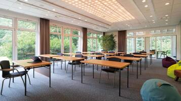 Un salón de conferencias con mesas, sillas y ventanas amplias.