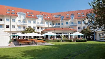 A courtyard with outdoor seating and a building with red-tiled roofs.
