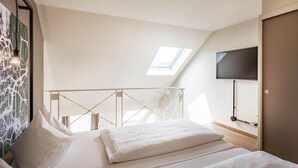 Een slaapkamer met een bed, een aan de muur bevestigde televisie en een dakraam.