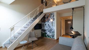 Un interior moderno con una escalera, un mural, un sofá y un escritorio con una computadora portátil.