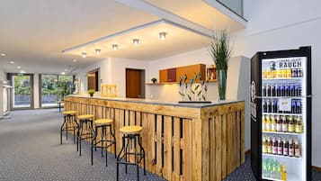 Zona de bar con taburetes de madera, un refrigerador lleno de bebidas y vistas al exterior.