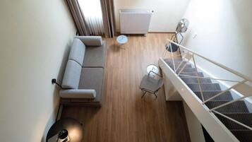 Un appartement moderne comprenant un canapé, une petite table ronde, une chaise, un radiateur et un escalier.