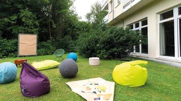Een gazon met kleurrijke zitkussens, een picknickdeken en een stoel.