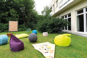 A grassy outdoor area with colorful bean bags, a picnic blanket, and a chair.