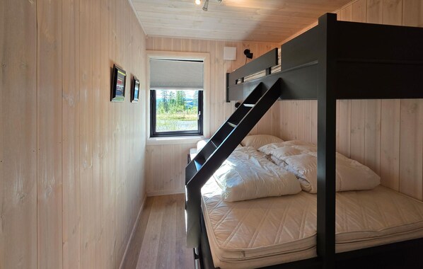 A bunk bed room with a window, wooden walls, and a ceiling light.