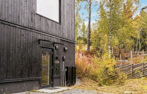 A modern building with a dark exterior, a glass door entrance, and a visible number '104'.