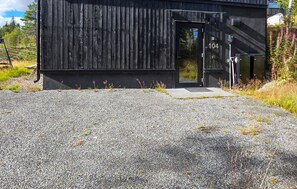A black building with a door marked '104' and a gravel driveway.