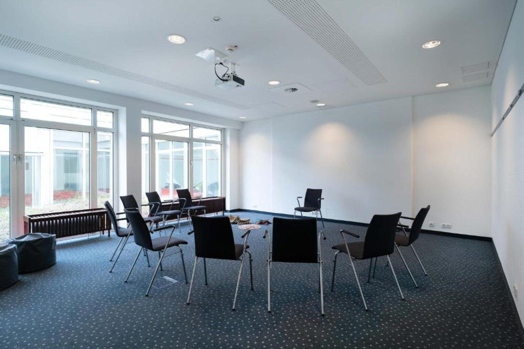 A conference room with a round table, six chairs, and a projector.