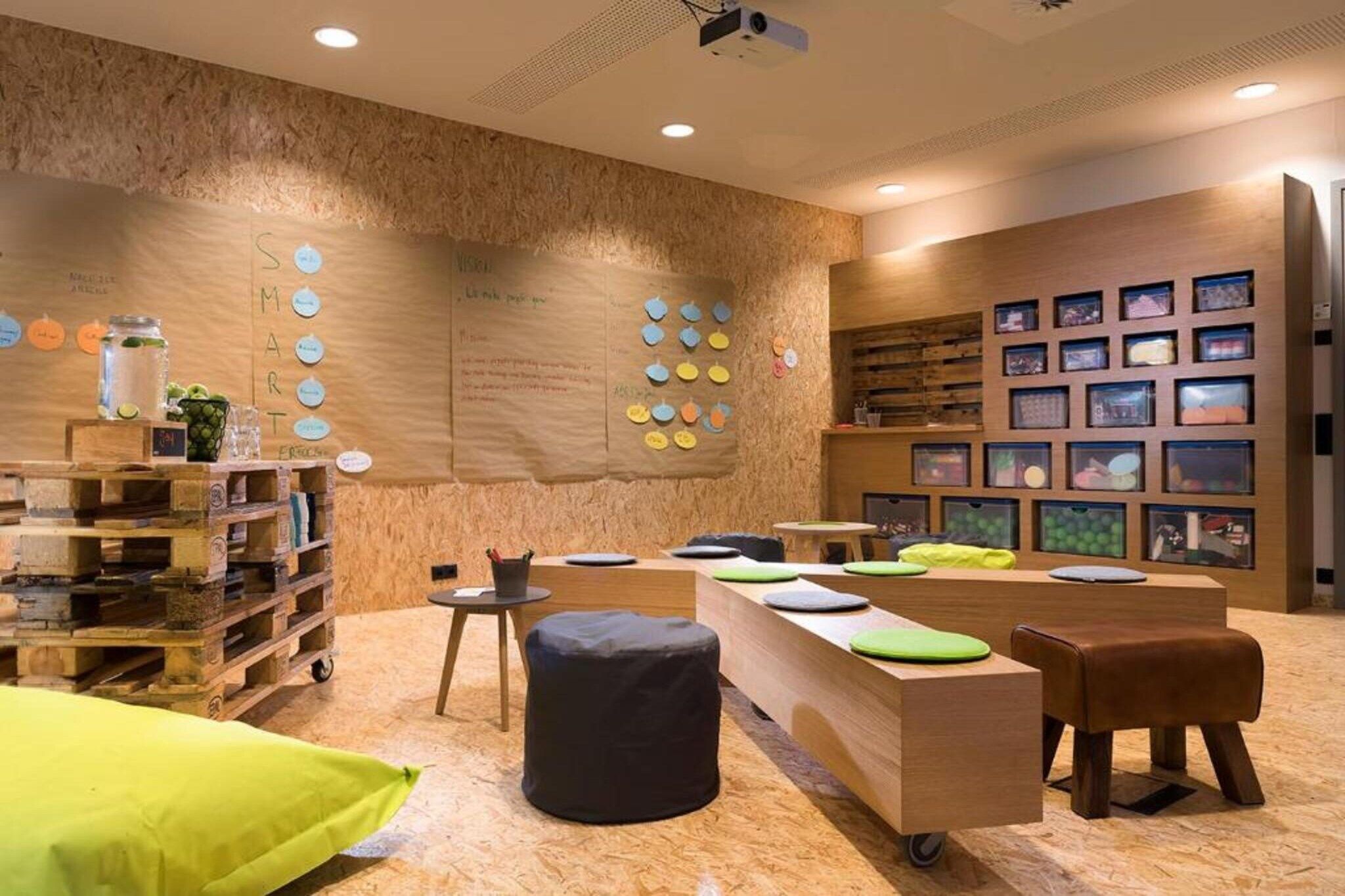 A modern interior with a wooden wall, a reception desk, and a seating area with cushions.