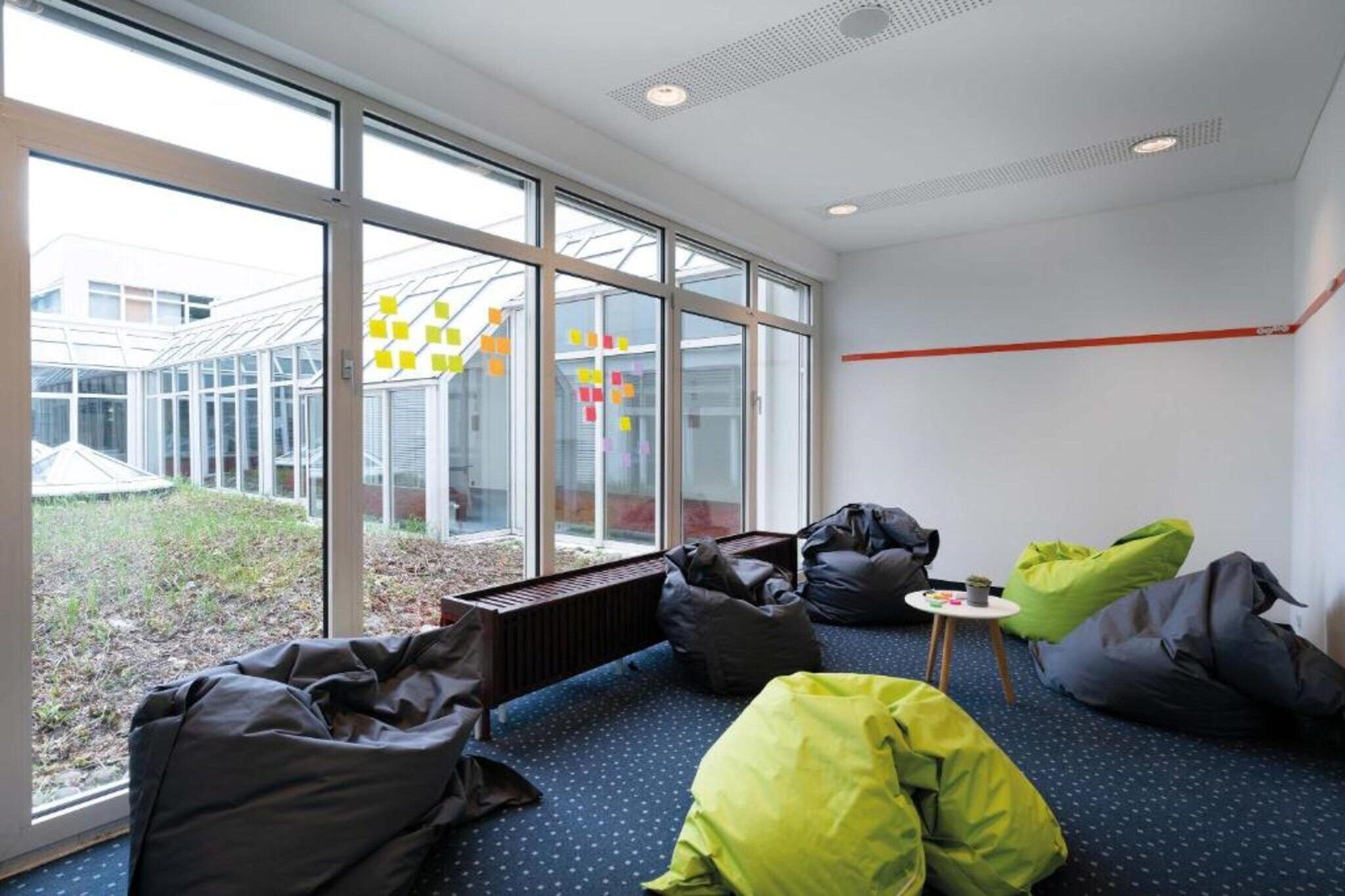 A modern interior with large windows, bean bags, and a small table with a plant.