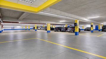 A multi-level parking garage with yellow and blue pillars, electric vehicle charging stations, and a clean, well-lit environment.