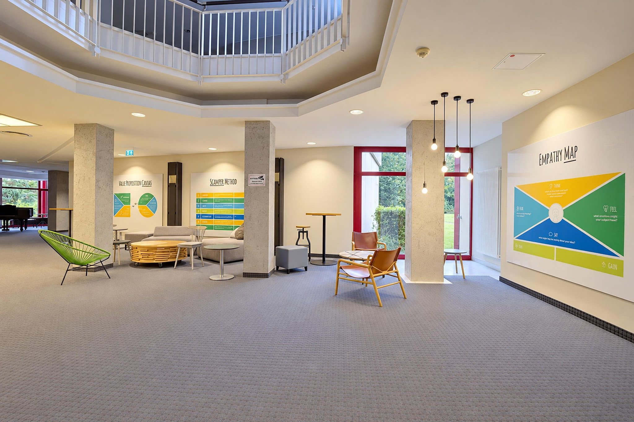 A spacious lobby with a high ceiling, a central seating area, and a large empathy map on the wall.