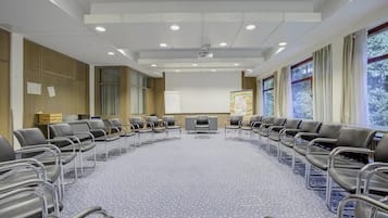 A conference room with a long table, chairs, a projector screen, and a presentation board.